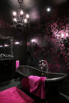 a fancy bathroom with pink rugs and chandelier above the bathtub,