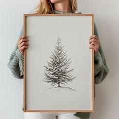 a woman holding up a drawing of a pine tree