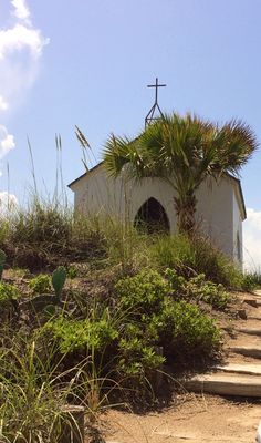 a small church on top of a hill with stairs leading up to the front door