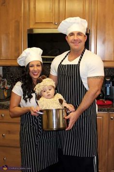 a man and woman in chef's outfits holding a baby wearing a teddy bear