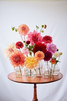 there are many different flowers in vases on the table