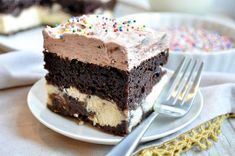 a slice of chocolate cake with frosting and sprinkles on a plate