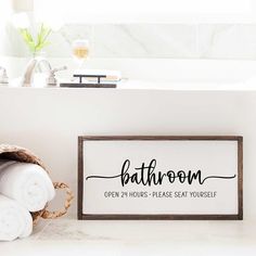 a bathroom sign sitting on the floor next to a pile of white towels and a basket