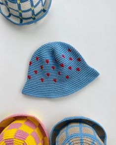 three crocheted hats sitting next to each other on top of a white surface