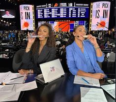 two women sitting at a table with papers and pencils in front of their mouths