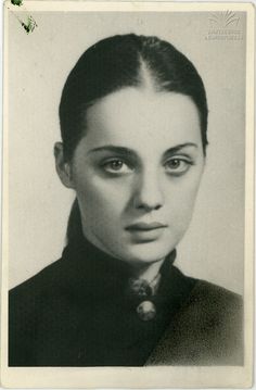 an old black and white photo of a woman with long hair wearing a collared shirt