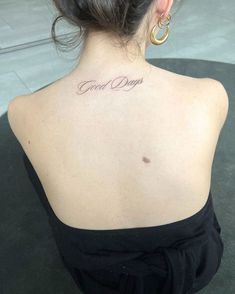 the back of a woman's neck with a small tattoo that reads good days