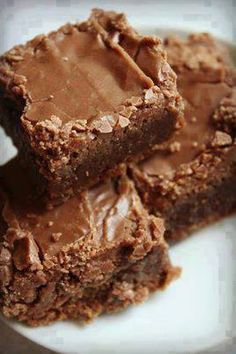 some brownies are on a white plate with chocolate frosting