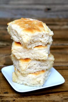 three biscuits stacked on top of each other on a white plate with a wooden table in the background