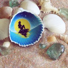 shells and seashells on the sand with a painted image of a man and woman