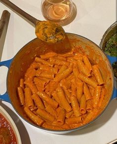 a pan filled with pasta and sauce on top of a white countertop next to other dishes