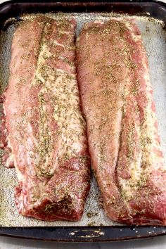 two raw steaks on a baking sheet covered in seasoning