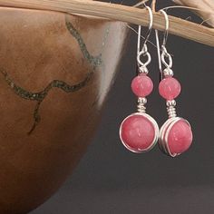 This unique pair of pink dangle earrings have handcrafted 924 Sterling Silver hooks, and are wire wrapped with bright silver plated wire to showcase pink rhodochrosite crystal gemstone. The earrings are fashioned to carry two rhodochrosite beads, a larger and a smaller one in each earring. The rhodochrosite has lovely consistent coral blush/ coral pink colour and is faintly mottled.  Drop length 3 cm Length from top of hook 4.5 cm width 1.2 cm For many other boho designs visit my Etsy shop at https://www.etsy.com/uk/shop/EarringsOfGemstone Postage and Packaging: Gift wrapping is available. While the default P&P option is set to Royal Mail 2nd class signed delivery (£1.50), an upgrade to Royal Mail 1st class signed delivery (£1.95) is available to select from the checkout basket before chec Pink Rose Quartz Earrings With Natural Stones, Pink Wire Wrapped Round Earrings, Pink Rose Quartz Jewelry With Ear Wire, Pink Round Sterling Silver Earrings, Pink Sterling Silver Round Earrings, Pink Rose Quartz Wire Wrapped Jewelry, Pink Rose Quartz Hand Wrapped Jewelry, Hand Wrapped Rose Quartz Pink Jewelry, Hand Wrapped Pink Rose Quartz Jewelry