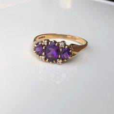 A charming vintage 9 carat yellow gold ring, displaying three striking Amethysts and four sparkling Diamonds in between them. The stones are held by a simple setting that really does frame the stones perfectly. CONDITION: Great condition, wear consistent with age and use. Please see photos for more detail. BAND WIDTH: 2mm SETTING LENGTH: 16mm STONE FACE: 8mm x 5mm SETTING HEIGHT: 4mm RING SIZE: UK: Z 1/2 | US: 12 3/4 WEIGHT: 3.8 grams (NZ) Classic Amethyst Birthstone Ring, Classic Purple Birthstone Ring, Vintage Three Stone 14k Gold Birthstone Ring, Classic Yellow Gold Three Stone Birthstone Ring, Vintage Three Stone Birthstone Ring For Gift, Vintage Three Stone Birthstone Ring As Gift, Vintage Formal Three Stone Birthstone Ring, Vintage Three Stone Birthstone Ring For Anniversary, Classic Gold Amethyst Multi-stone Ring