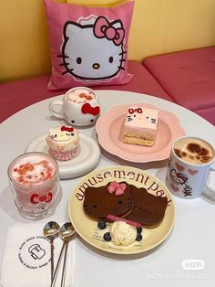 hello kitty themed desserts and drinks on a table with pink pillows, spoons and utensils