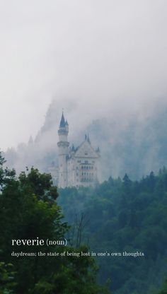 a castle on top of a hill with trees in the foreground and fog over it