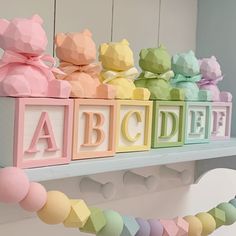 colorful wooden blocks spelling out the word abcdef on a white shelf with pink, yellow, green, and blue letters