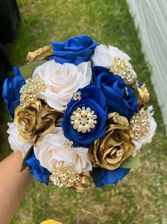 a bridal bouquet with blue, white and gold flowers is held in someone's hand