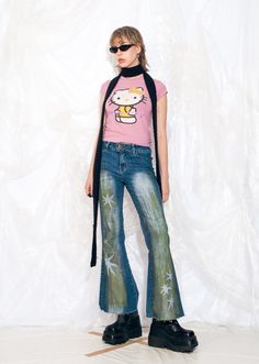 a woman in pink shirt and jeans with hello kitty t - shirt over her shoulder