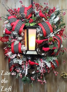 a christmas wreath with a lit candle in the center and red ribbon around it on a door