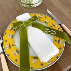 a plate with a green bow on it next to silverware and utensils