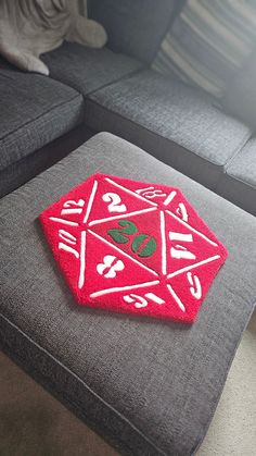 a red rug with white letters and numbers on it sitting on a gray couch in front of a window