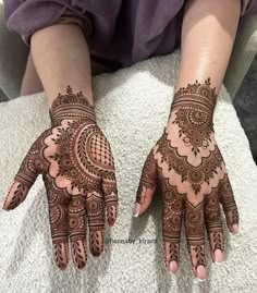 two hands with henna designs on them, one is showing it's intricate design