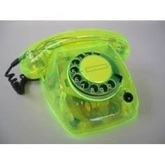 an old fashioned green phone sitting on top of a white table with a cord attached to it