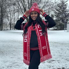 a woman is standing in the snow wearing a red scarf and black leggings