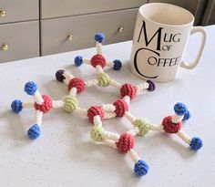 there are many small crocheted beads on the table next to a coffee mug