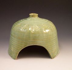 a green vase sitting on top of a white table