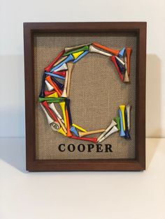 a wooden frame that has some colorful pieces in it and the word cooper written on it