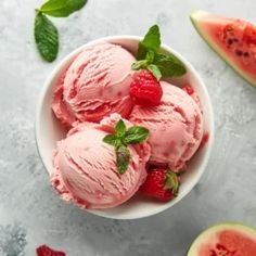 three scoops of ice cream with raspberries and mint leaves in a bowl