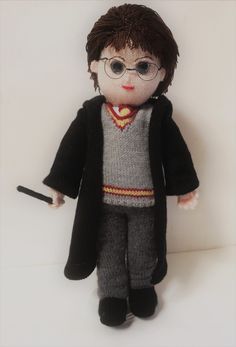 a stuffed doll with glasses and a harry potter sweater is posed on a white surface