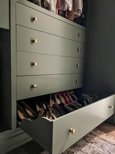 an organized closet with shoes and handbags in the bottom drawer, on carpeted floor