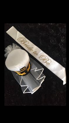 a white cake sitting on top of a table next to a ribbon and cupcake