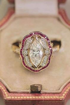 a fancy engagement ring in a box with red and gold trimmings on it