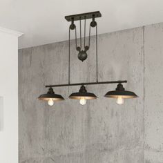 three lights hanging from the ceiling in a room with concrete walls and flooring behind them