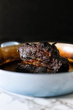 two pieces of chocolate cake in a white bowl on a marble counter top next to a banana