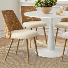 a white table with four chairs and a vase filled with flowers on top of it