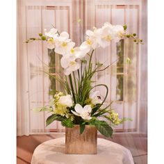 white flowers are in a wooden vase on a table