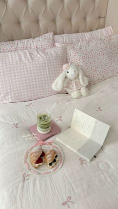 a stuffed animal sitting on top of a bed next to donuts and an open book