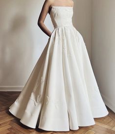 a woman in a white dress standing on a wooden floor