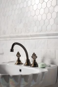 a bathroom sink with two faucets and soap dispenser