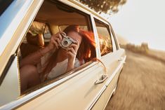 a woman taking a photo in the back seat of a car while holding a camera