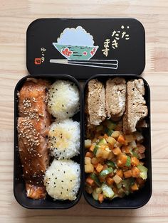 two black trays filled with food on top of a wooden table