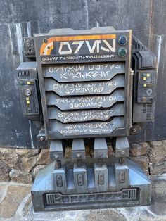 an old machine with writing on it sitting in front of a stone wall and door