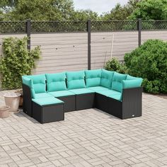 an outdoor sectional sofa with blue cushions on a brick patio in front of a fence