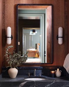 a bathroom sink with a mirror above it and vases on the counter next to it