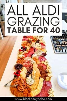 a long table covered in lots of different types of food and words that read, all aldi grazing table for 40